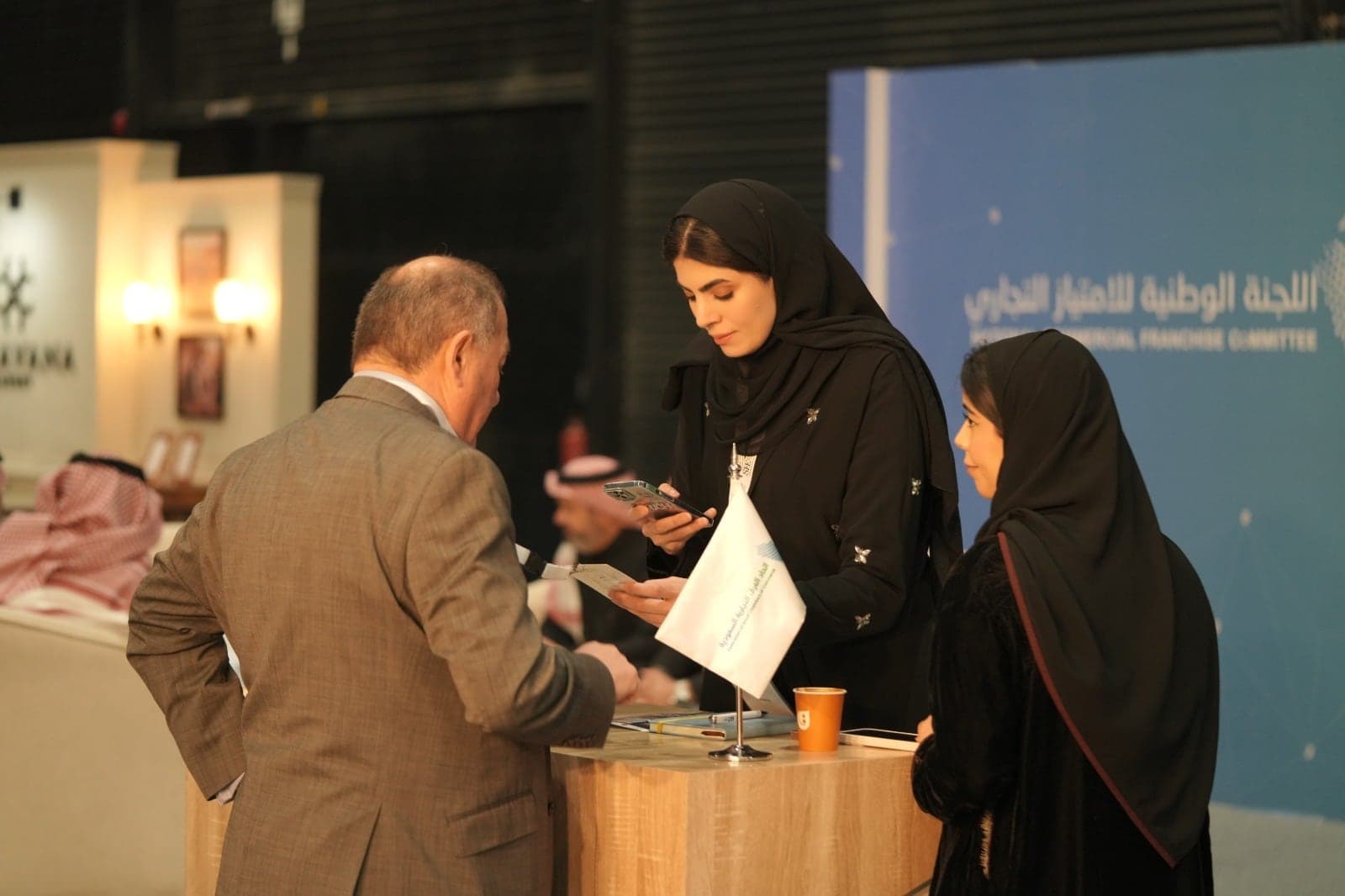 زائر يتحدث مع ممثلة اللجنة الوطنية للامتياز التجاري في جناحها